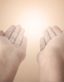 Two hands are held open and upward toward a glowing, soft white light, symbolizing healing energy.