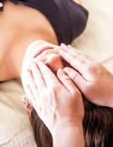 A practitioner’s hands are placed gently over a person’s face and forehead during a Reiki healing session.