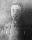 Grayscale portrait of a man with a mustache and goatee, wearing a traditional Japanese kimono.