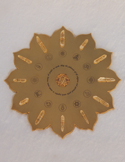 A gold lotus-shaped crystal grid featuring various symbols and clear quartz points arranged in a circle.