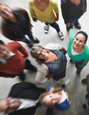 High-angle, slightly blurred shot of a diverse group of people looking upward and smiling.