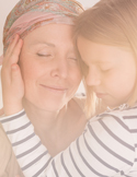 A mother in a headscarf and her young daughter share a gentle, forehead-to-forehead embrace with eyes closed.