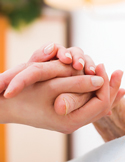 Two people holding hands gently in a supportive, comforting gesture of care and connection.