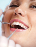 Close-up of a woman smiling at the dentist, showcasing healthy white teeth during an exam.