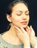 Close-up of a practitioner’s hands gently touching a woman’s neck and jawline during a wellness exam.