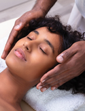 Close-up of a person's hands hovering over a woman's face during a calming energy healing session.