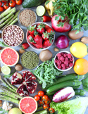 A flat lay of vibrant healthy foods including berries, greens, citrus, and legumes.