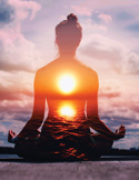 Silhouette of a person meditating with a glowing sun and ocean scene blended within their body against a colorful sky.