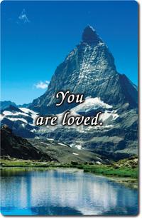 Mountain scene with a clear blue sky and lake reflection, featuring the uplifting message “You are loved” across the center.