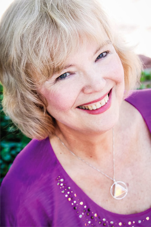 Portrait of Laurelle Gaia wearing a purple top and a silver necklace, photographed outdoors.