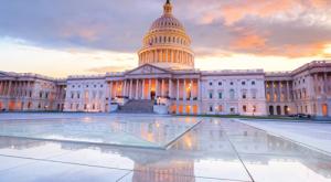 U.S. Capitol building at sunrise, its dome and columns glowing in warm light.